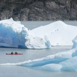 kayaking on grey lake among icebergs